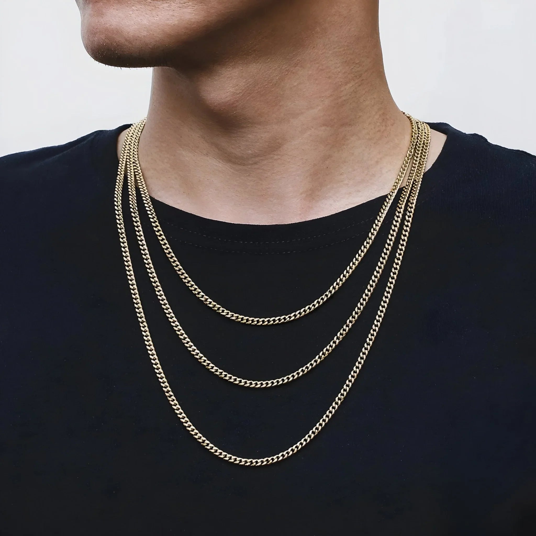 Mann mit mehreren goldenen Ketten auf schwarzem T-Shirt, modischer Halsschmuck