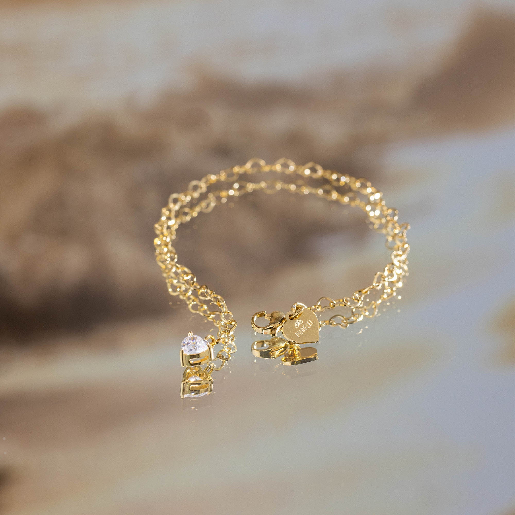 Ultra Close-up of PURELEI Endless Love Bracelet with heart-shaped gold chain links and sparkling zirconia heart pendant, elegant and timeless.