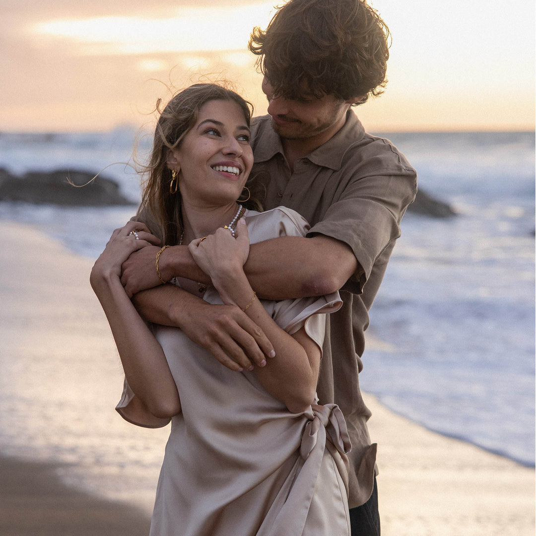 Woman wearing PURELEI Endless Love Bracelet on her left hand, embraced by her smiling partner, both radiating happiness.