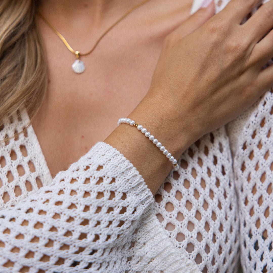 Woman wearing the elegant PURELEI 18K gold Finesse Bracelet with freshwater pearls on her right arm.