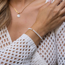 Woman wearing the elegant PURELEI 18K gold Finesse Bracelet with freshwater pearls on her right arm.