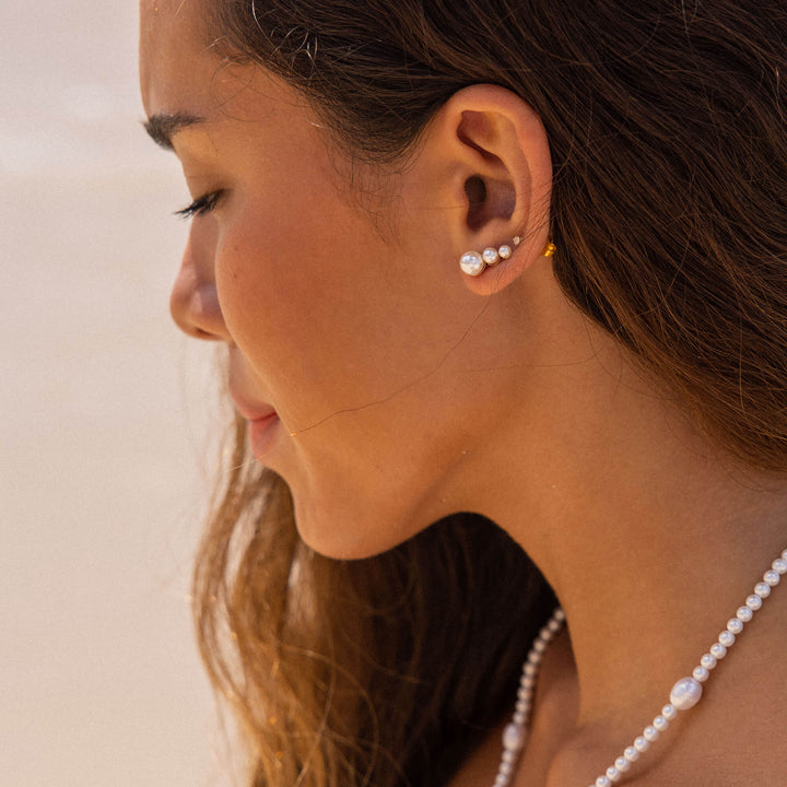 Woman wearing PURELEI Finesse Earrings in 18K Gold-Plated on her left ear, showcasing the elegant pearl ear cuff design.