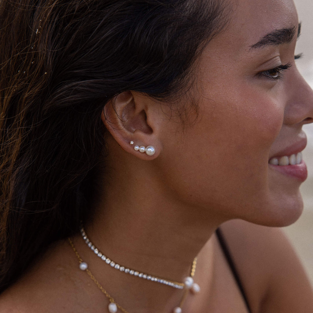 Woman wearing PURELEI Finesse Earrings in Stainless Steel on her right ear, showcasing the elegant pearl ear cuff design.