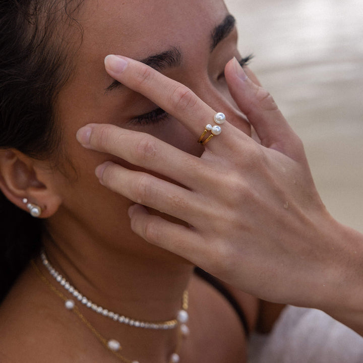 Woman wearing the PURELEI Finesse Ring in gold on her right hand, styled with matching Finesse necklace, bracelet, and earrings.