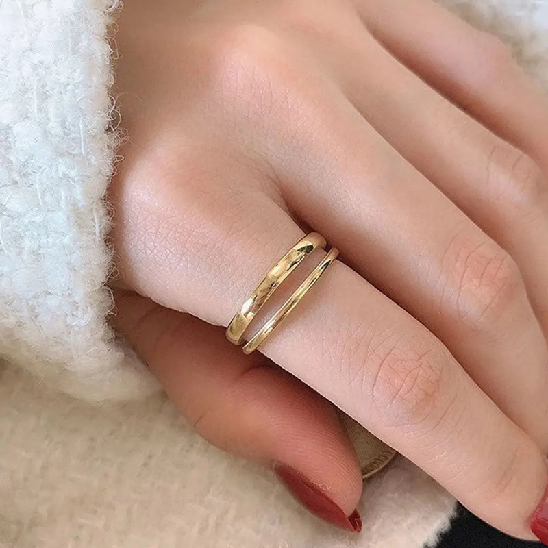 Zarter goldener Doppelring am Finger, elegante Schmuckmode, Nahaufnahme auf Hand