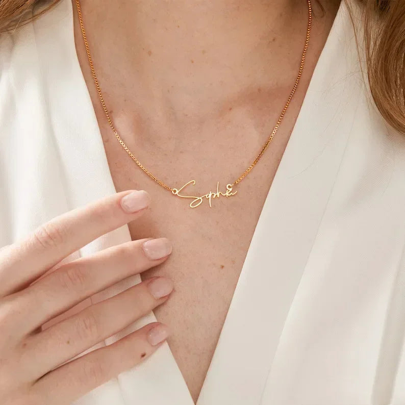 Goldene Namenskette mit dem Schriftzug 'Sophie' an einer Person mit weißem Oberteil