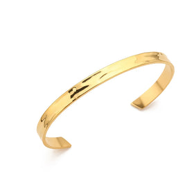 Minimalistische goldene Armspange aus poliertem Metall auf weißem Hintergrund