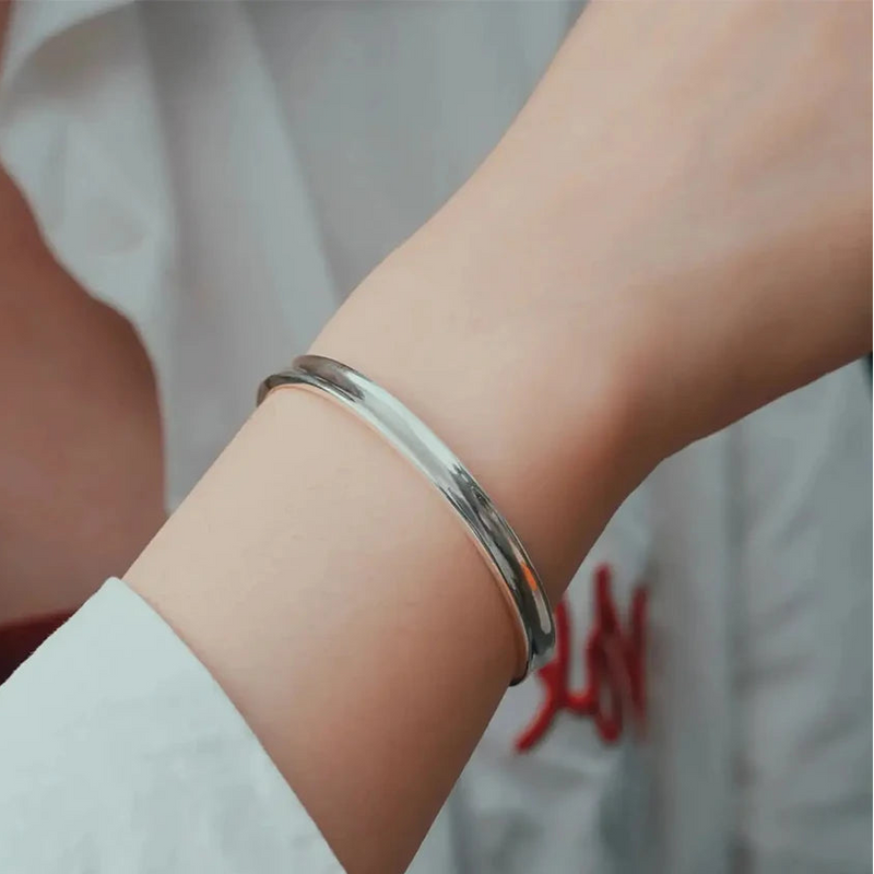 Damenarm mit glänzendem Edelstahl-Armreif, schlichtes Schmuckdesign, 18K Weißgold Look