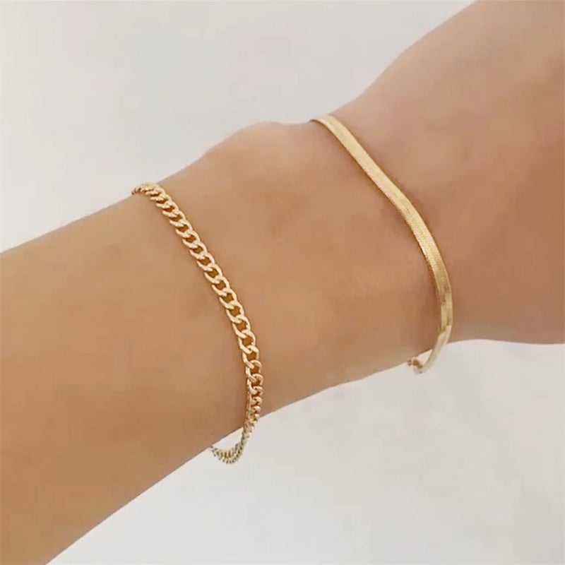 Zwei filigrane goldene Armbänder an einem Handgelenk, Schmuck auf heller Haut