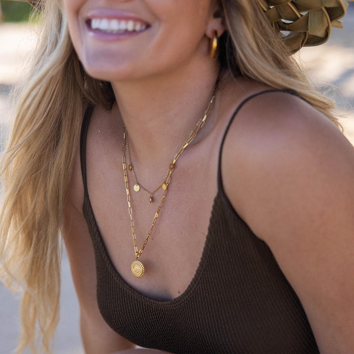 Woman wearing the PURELEI Kalea Necklace in gold, layered elegantly with matching necklaces for a chic and stylish look.