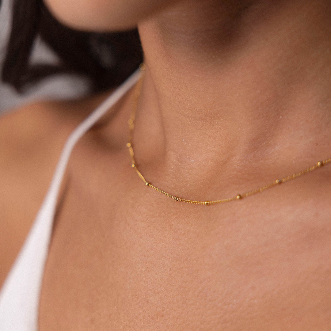 Woman wearing the PURELEI Li'ili'i Necklace Gold, a delicate 18K gold-plated chain styled elegantly for layering.