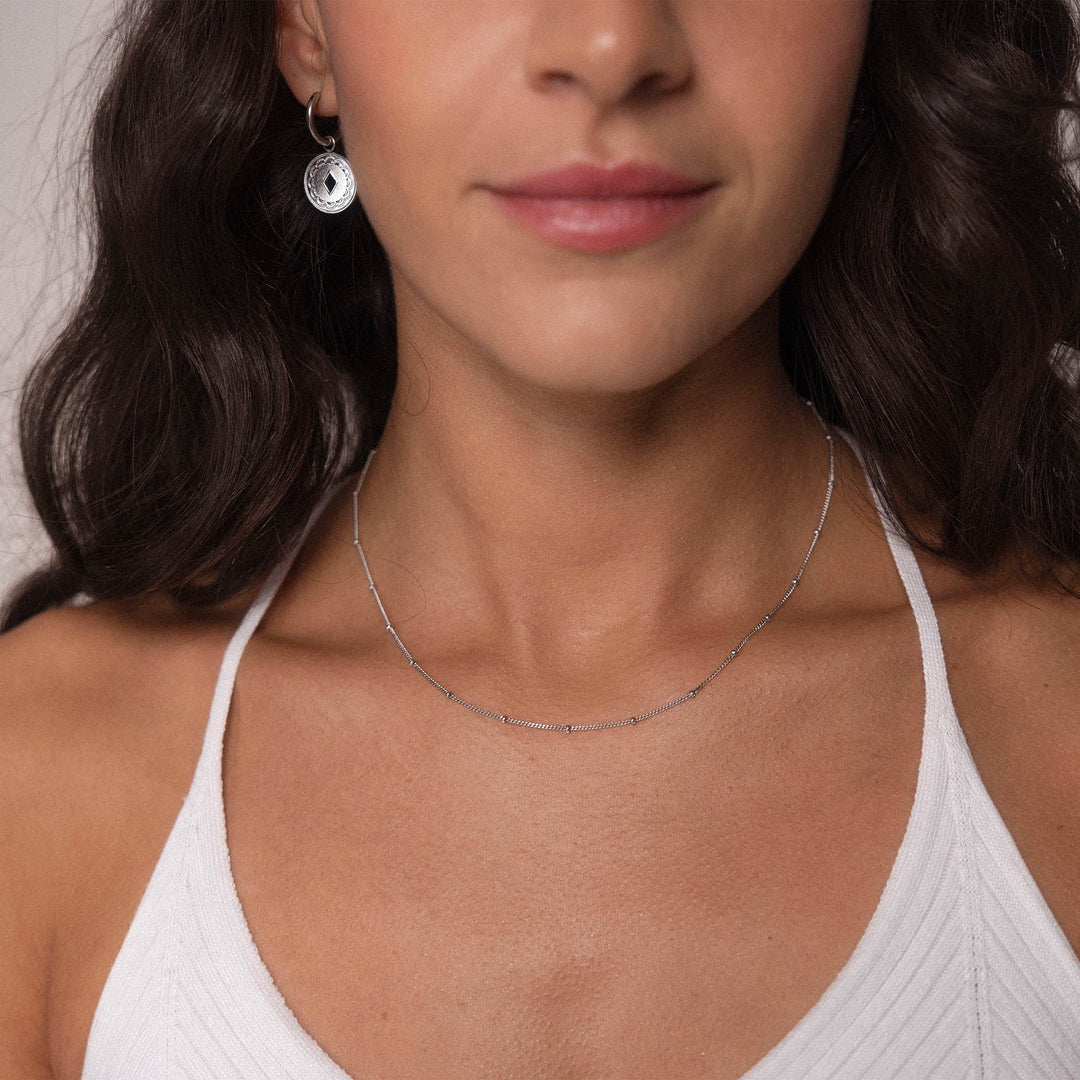 Woman wearing the PURELEI Li'ili'i Necklace Silver, a delicate stainless steel chain styled elegantly for layering.