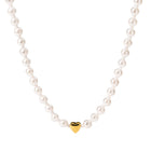 Close-up of the PURELEI Lovely Necklace in gold, featuring a heart pendant and a mix of seashell and glass pearls for an elegant look.