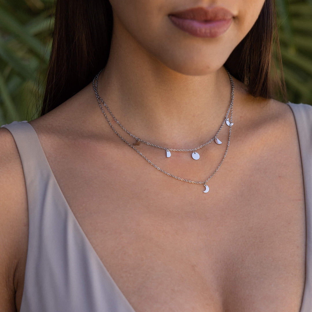 Woman wearing the PURELEI Luna silver necklace with delicate moon phase charms, elegantly showcasing its celestial design.