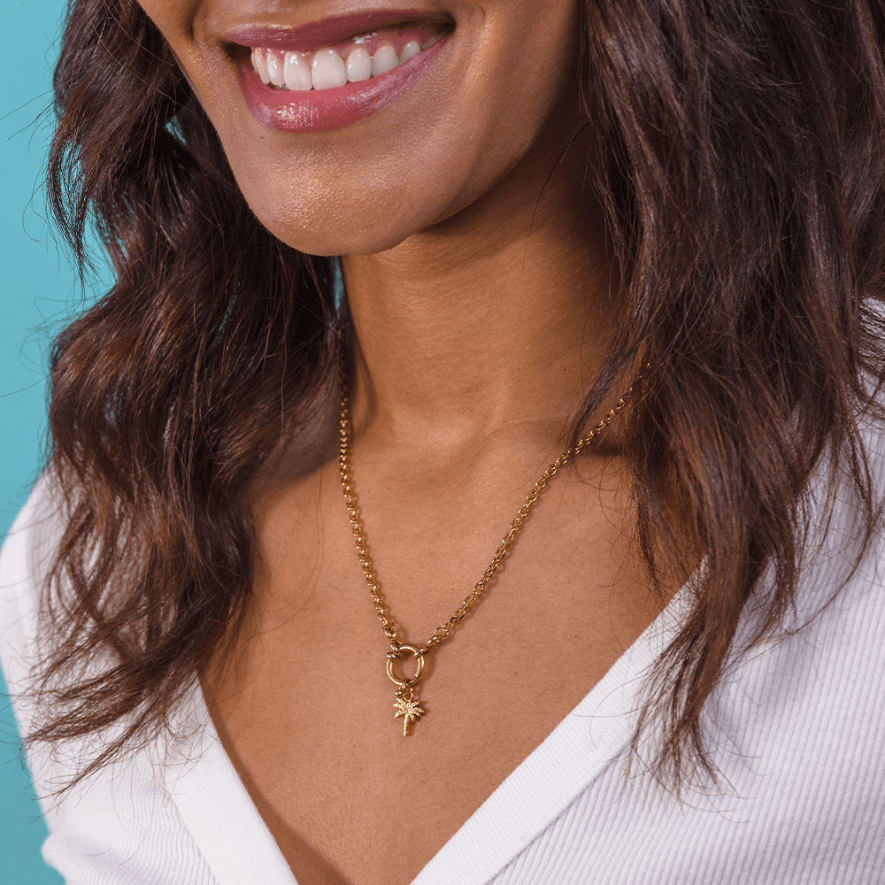 Woman wearing PURELEI Palmtree Charm on a matching gold necklace, showcasing its elegant and personalized design.