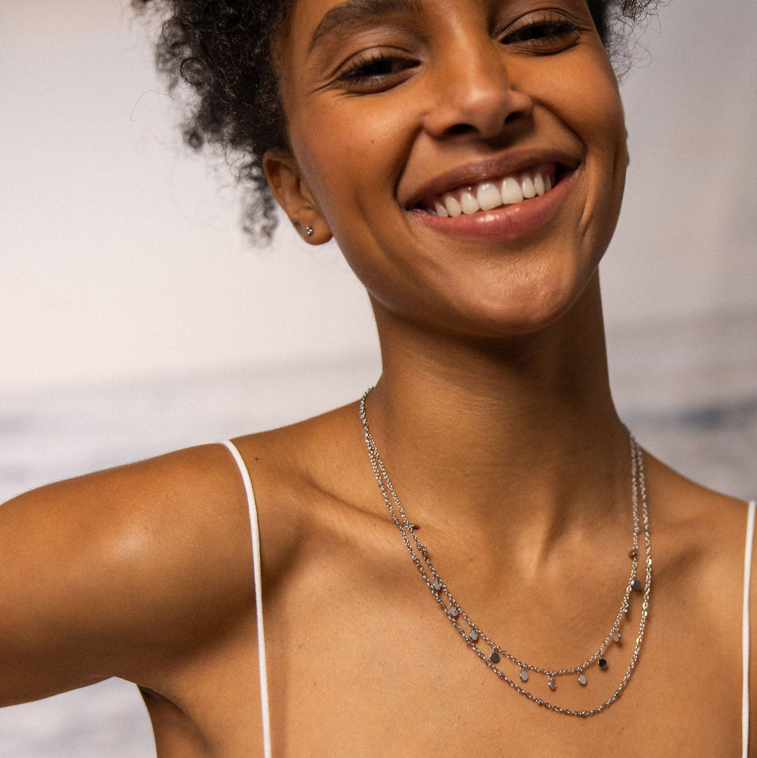 Woman wearing PURELEI Plain Necklace Silver: double-layered design with beads and coin pendants, adding elegance to her outfit.