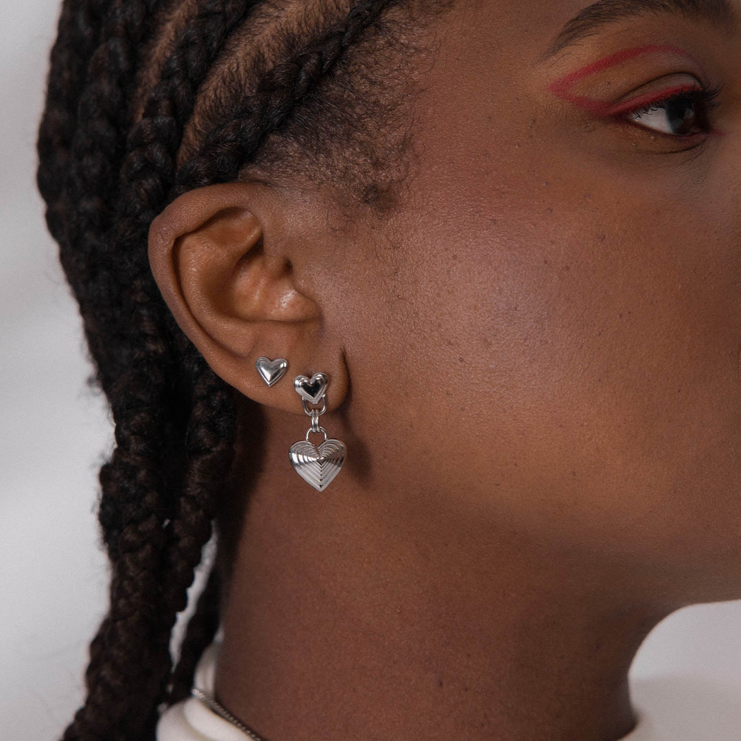 Woman wearing PURELEI Secret Love Earrings Silver on her right ear, paired with another Silver earring for a layered, elegant look.