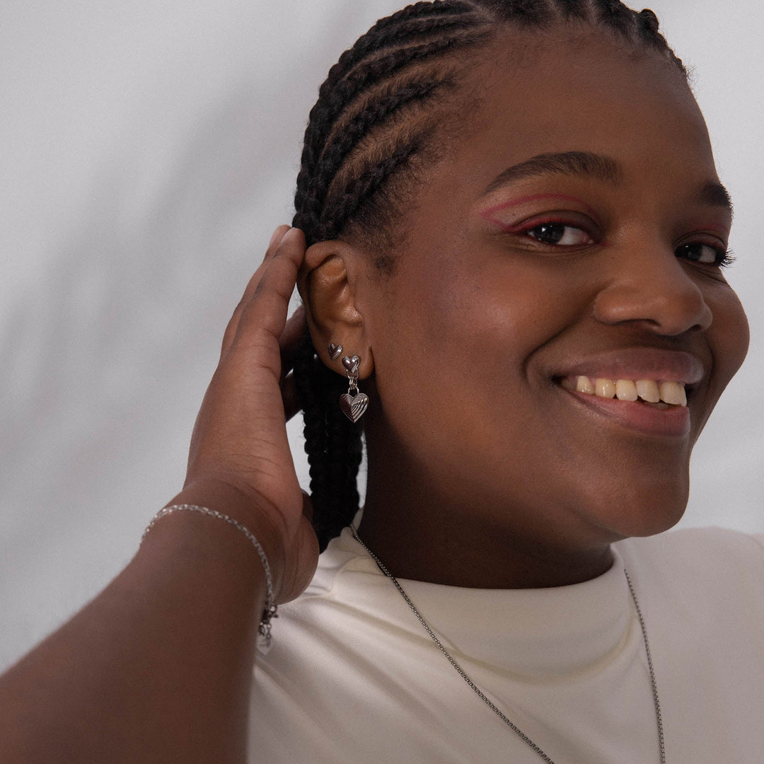 Woman wearing PURELEI Secret Love Earrings Silver on her right ear, paired with another Silver earring for a layered, elegant look.