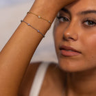 Woman wearing PURELEI Spotlight Bracelets in silver and gold on her right arm, showcasing elegant zirconia stones and adjustable design.