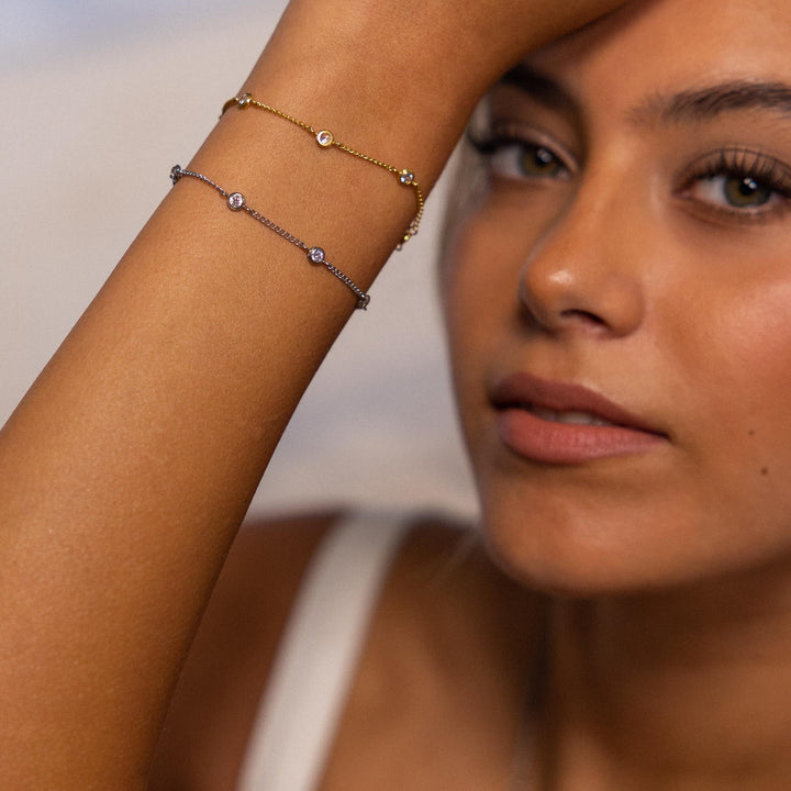 Woman wearing PURELEI Spotlight Bracelets in silver and gold on her right arm, showcasing elegant zirconia stones and adjustable design.